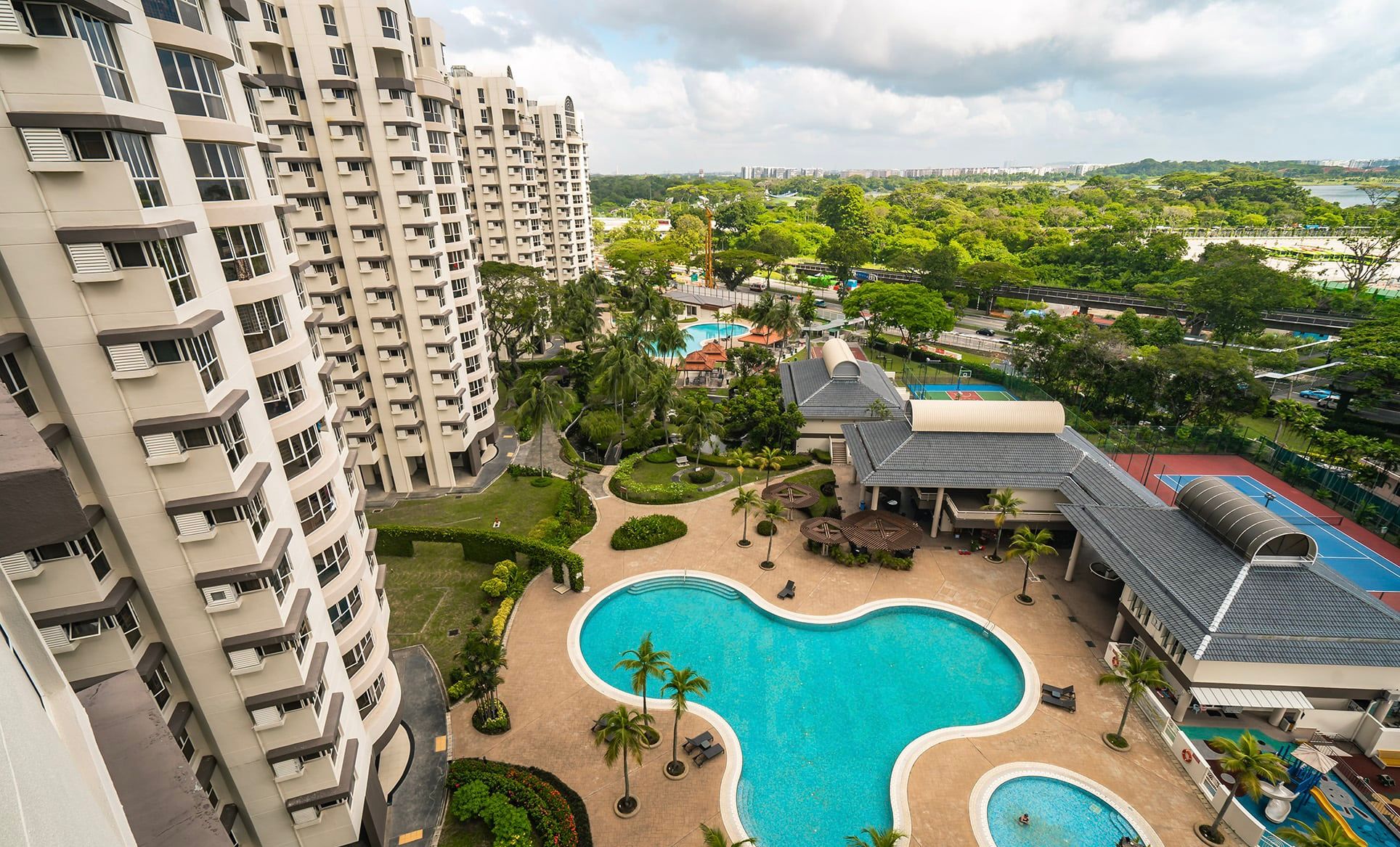 Bullion Park aerial view — the full plot with three of the seven towers, the main pool deck, tennis courts, and the surrounding greenery toward Lentor MRT